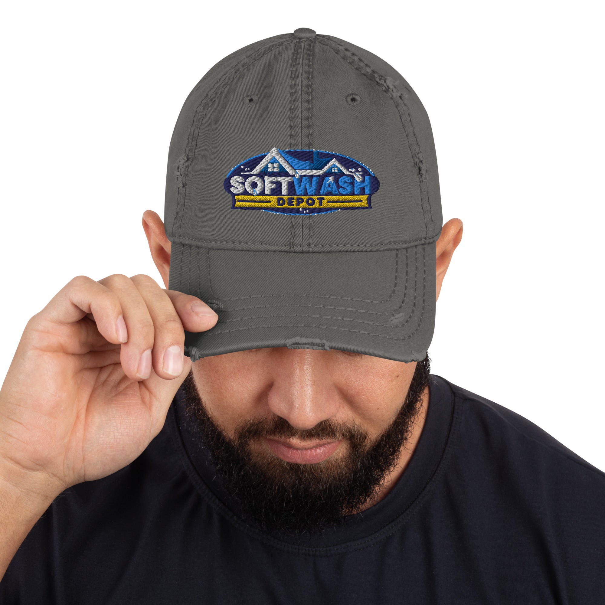 Man wearing a black distressed dad hat with the Soft Wash Depot embroidered logo on the front, adjusting the brim while looking down. - Soft Wash Depot