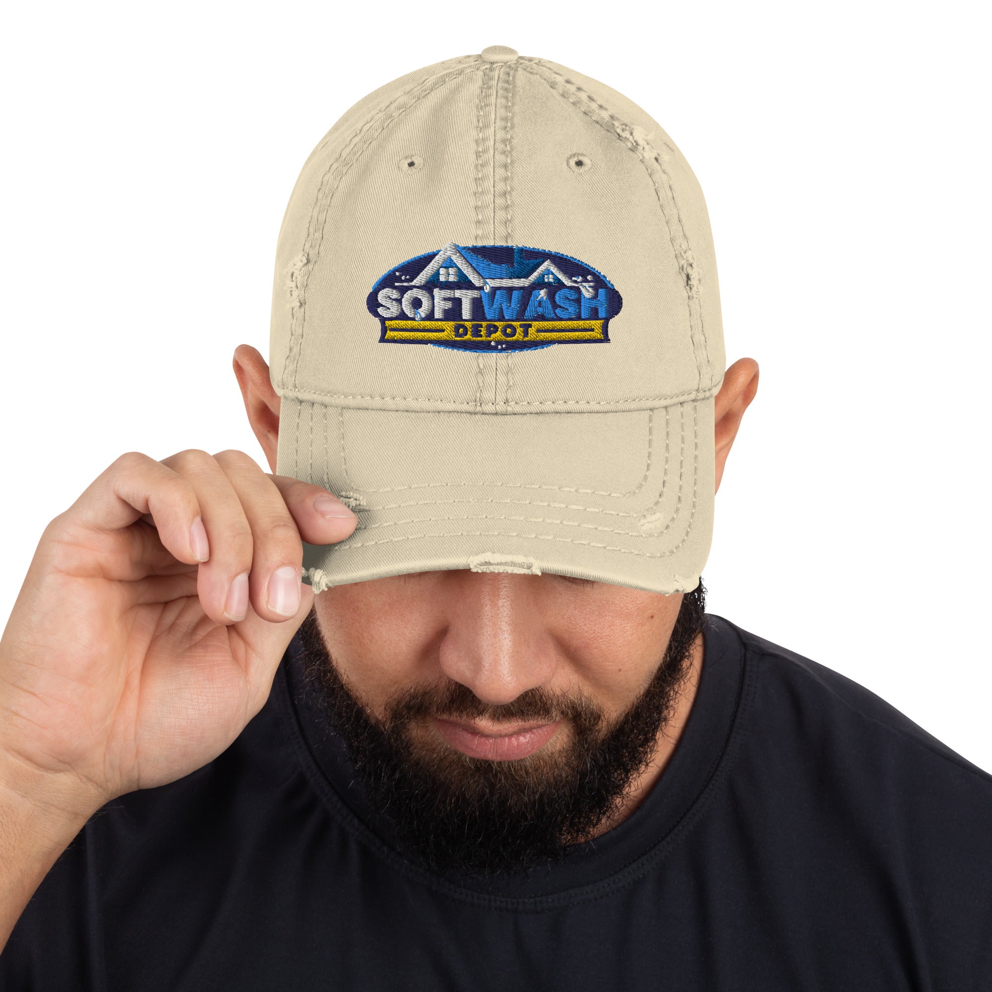 Man wearing a black distressed dad hat with the Soft Wash Depot embroidered logo on the front, adjusting the brim while looking down. - Soft Wash Depot